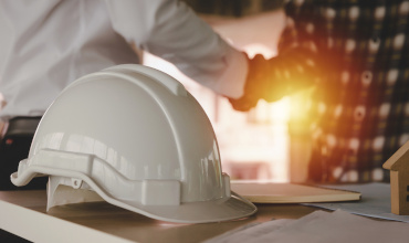 construction worker team hands shaking greeting start up plan new project contract behind white safety helmet on workplace desk in office center at construction site, partnership, contractor concept