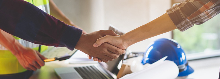 Two people shaking hands in a construction or contractor setting