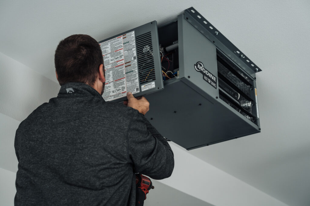 A contractor installing a Modine Hot Dawg gas-fired power-vented unit heater, model HD45, in a residential garage