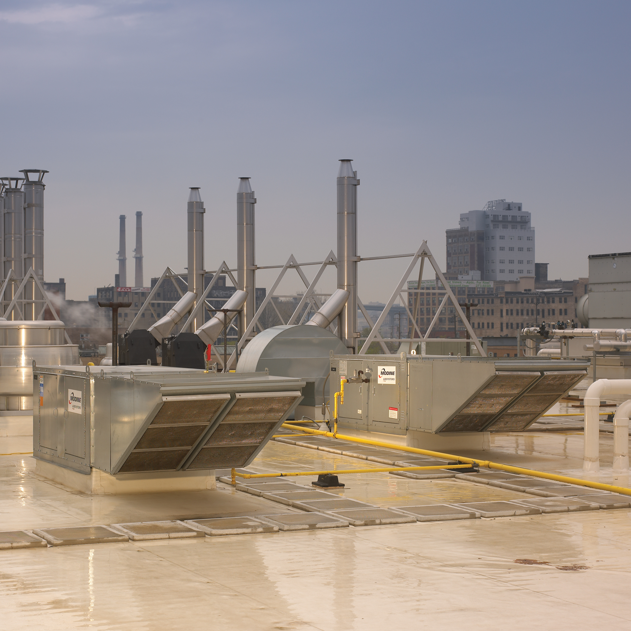 Two Direct-fired Modine make-up air systems mounted on the rooftop of a building in an industrial city